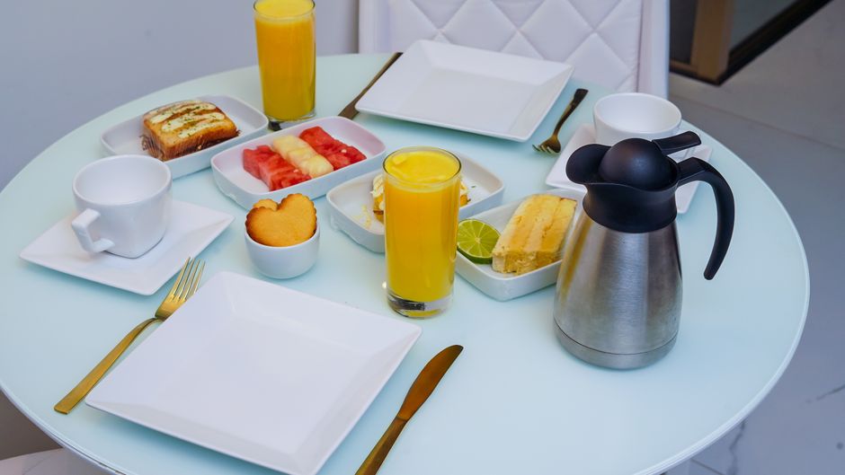Mesa de desayuno con pasteles, fruta fresca y jugo de naranja