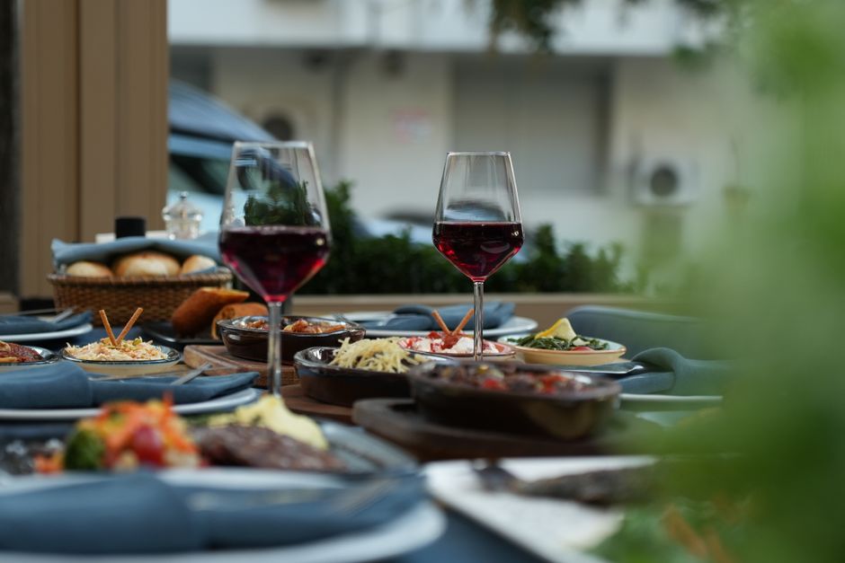 Mesa exterior lujosa con vino tinto y variedad de platos gourmet para una experiencia gastronómica sofisticada